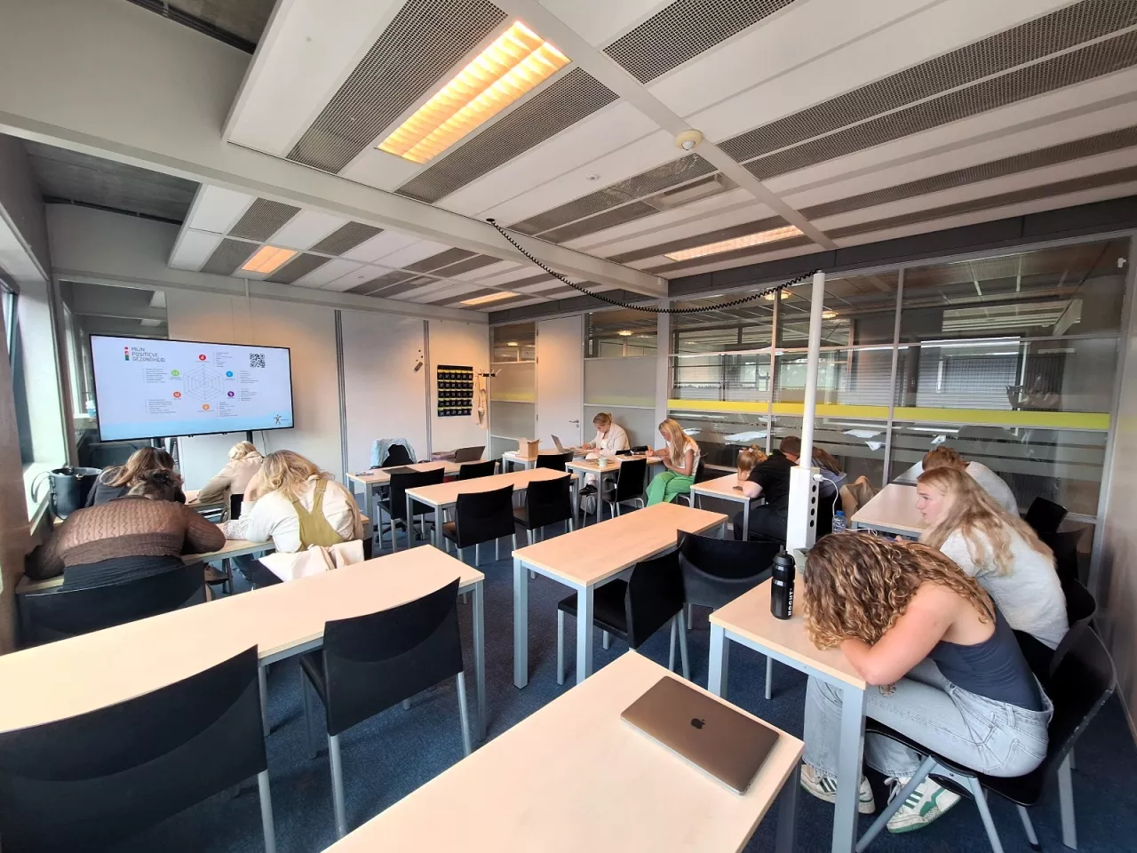 Klaslokaal met studenten Zorg en Welzijn die bezig zijn met het invullen van het spinnenweb van Positieve Gezondheid