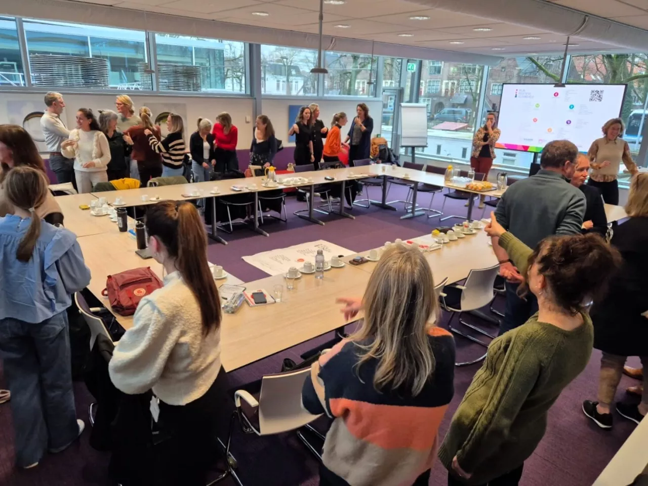 Volle zaal met mensen tijdens een presentatie.