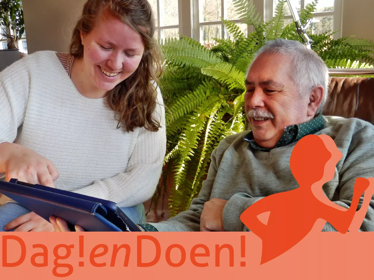 Een jongere vrouw geeft uitleg over de tablet aan een oudere meneer