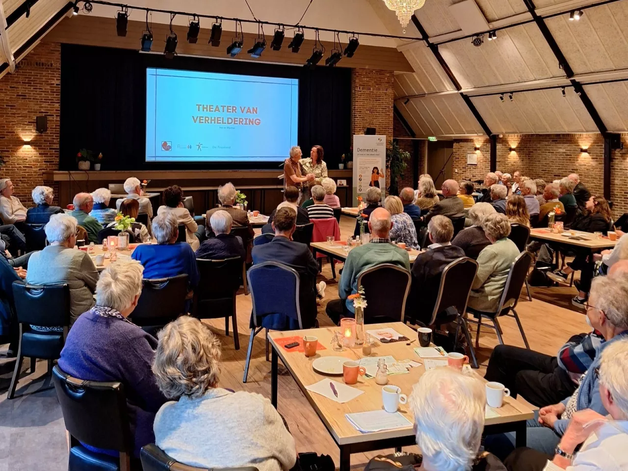 Een overzichtsfoto van een zaal vol mensen bij de bijeenkomst Dementie en Mantelzorg